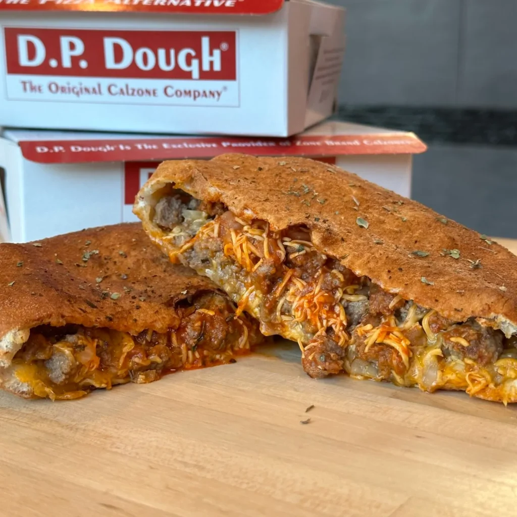 D.P. Dough calzone, sliced to reveal melty cheese and savory fillings, served in a branded takeout box