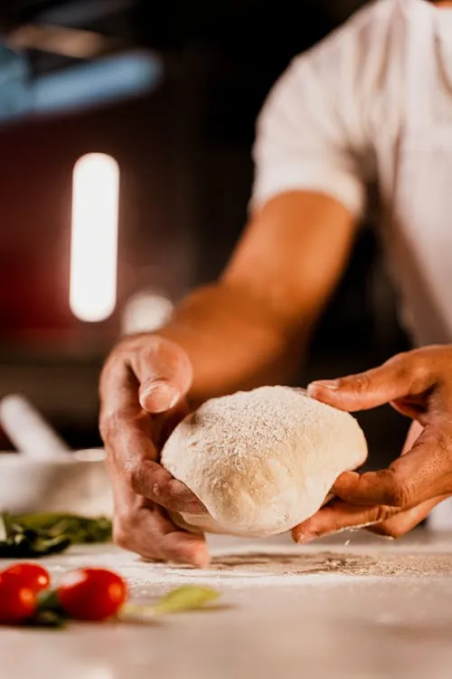 Close‑up of a chef’s hands shaping artisanal pizza dough