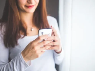 Girl in white blouse checking white mobile phone, featured in the article 'Who Is Calling From (662) 255-3743? Everything You Need to Know About This Mississippi Number.