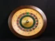 A close-up, top-down view of a classic wooden roulette wheel with red, black, and green numbered slots, centered against a dark background.