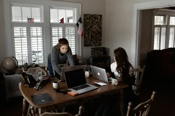 Two people collaborating on their small business, on laptops in a home office setting.