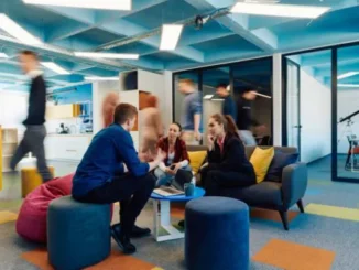People collaborating in a modern, activity-based office setting, discussing ideas in a comfortable lounge area.