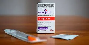 Mounjaro box (tirzepatide 15 mg/0.5 mL) standing upright on a wooden surface, with a sealed injection component and an alcohol swab packet in the foreground.