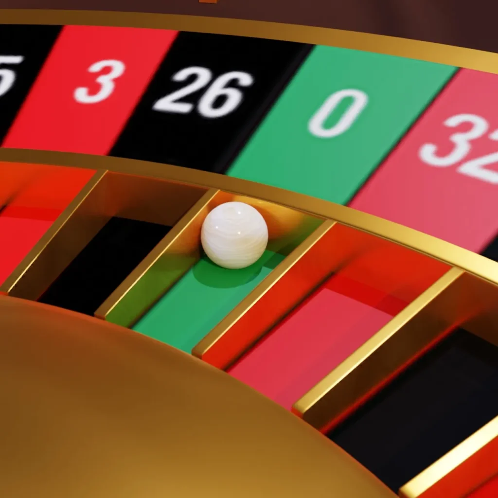 A close-up, angled view of a roulette wheel with a white ball resting in the green '0' slot.