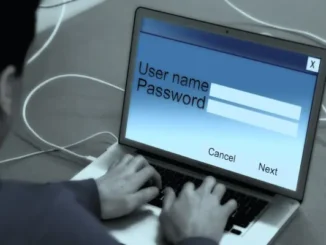 Person typing username and password on a laptop login screen.