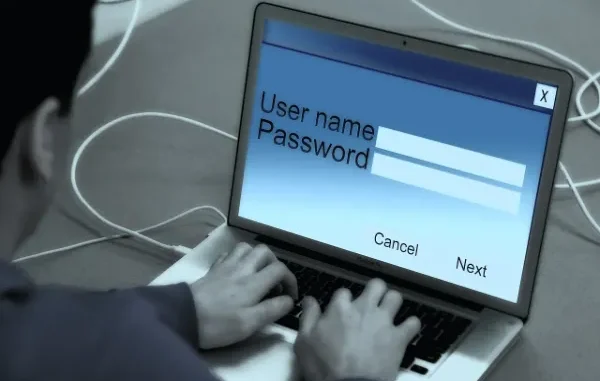 Person typing username and password on a laptop login screen.