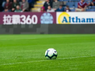 サッカー場の一部と観客席で試合を見守る人々の様子