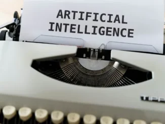 A vintage white typewriter with a piece of paper inserted that reads "ARTIFICIAL INTELLIGENCE" in bold black letters.