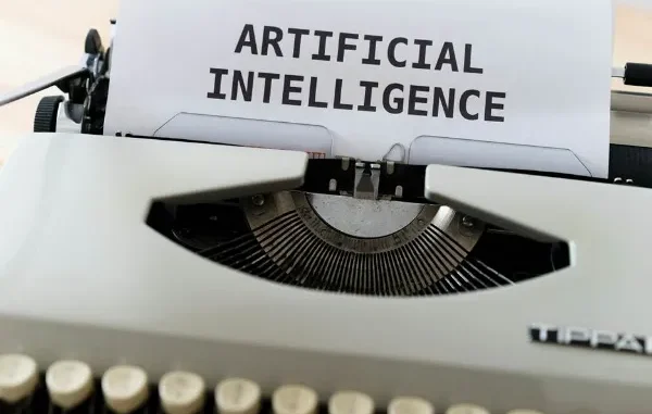 The AI-Powered Pen: How Students Are Revolutionizing Writing A vintage white typewriter with a piece of paper inserted that reads "ARTIFICIAL INTELLIGENCE" in bold black letters.