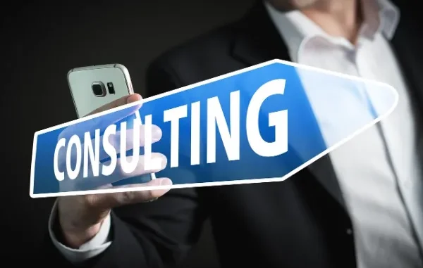 Professional Consulting Guidance A person in a suit holding a smartphone and a blue arrow sign with the word "CONSULTING," symbolizing expert guidance for business solutions.