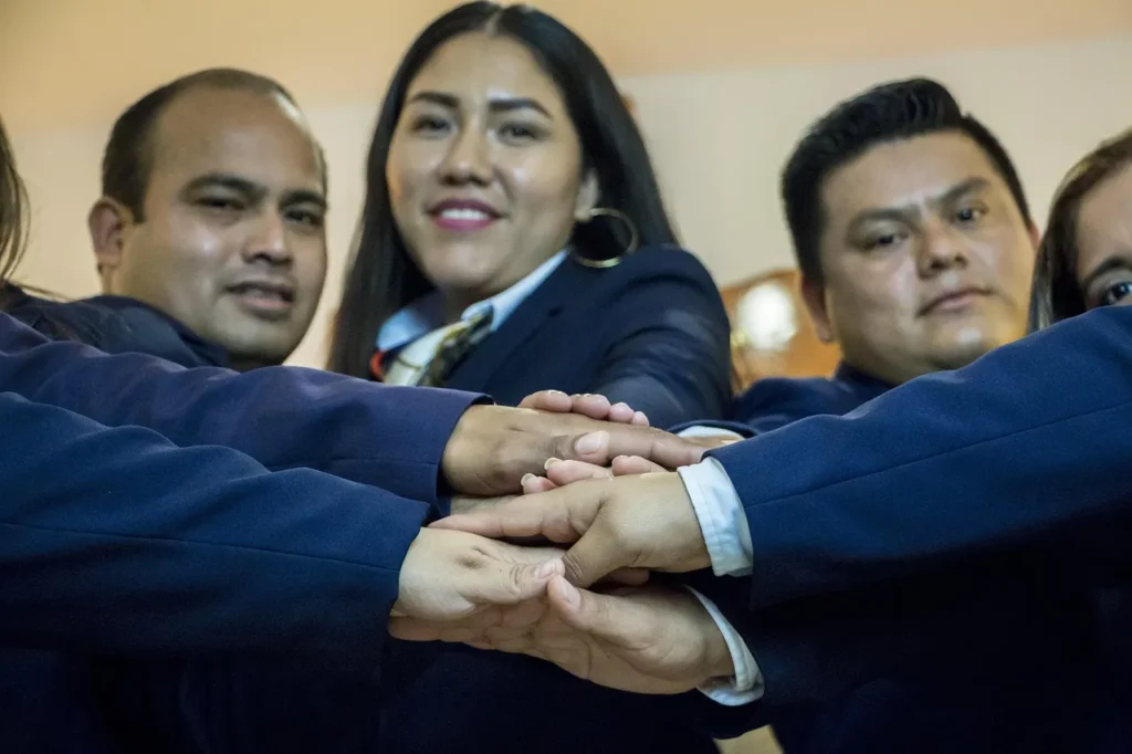 A team of professionals in suits with their hands stacked together, symbolizing collaboration, unity, and a strong partnership, representing a consulting team.