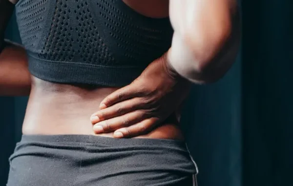 Seeking Relief: Delta 8 Gummies for Anxiety and Pain A hand gently holding a person's lower back, indicating potential pain or discomfort.
