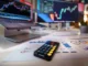 A desk setup with a laptop and a large monitor displaying forex trading charts, along with financial documents, a calculator, and a smartphone, symbolizing financial analysis and partnership opportunities.