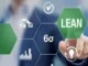 A hand touching a virtual screen with interconnected hexagonal icons, one prominently displaying "LEAN" and another "6σ" (Six Sigma), representing the Lean Six Sigma methodology for process improvement.