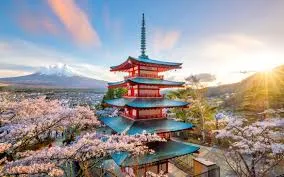 Chureito Pagoda, a five-story red and blue pagoda, surrounded by pink cherry blossoms, with snow-capped Mount Fuji in the background under a vibrant sunset sky.