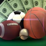 A football, soccer ball, basketball, and baseball in front of fanned-out hundred-dollar bills.