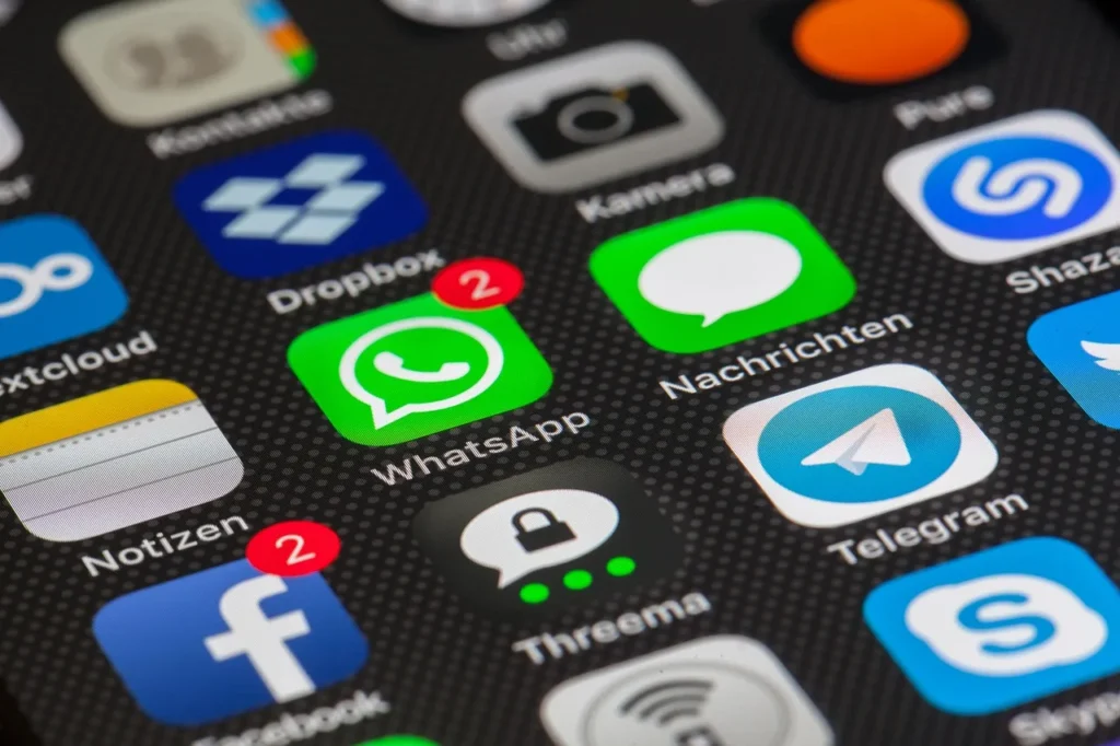 A close-up view of a smartphone screen displaying various application icons, including prominent WhatsApp and Telegram icons, some with notification badges.