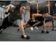Two people performing a renegade row exercise with dumbbells in a gym, focusing on strength training.