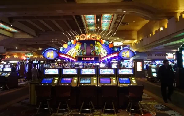Casino floor with rows of video poker machines under a brightly lit "POKER" sign displaying a progressive jackpot amount.