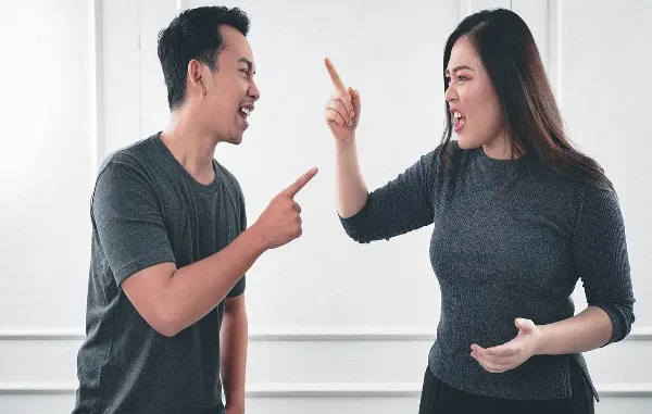 A man and woman angrily yelling and pointing at each other, representing the emotional conflict and distractions that can arise during divorce.