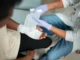 A medical professional or first responder is shown bandaging the hand of an injured person, illustrating the need for prompt medical care following an accident.