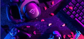 A top-down view of gaming accessories including headphones, a controller, and a keyboard, scattered on a dark surface under vibrant pink and blue neon lighting, with small heart-shaped candies interspersed.