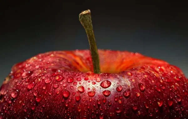 Healthy Apple for Hair Restoration Nutrition A close-up of a vibrant red apple covered in water droplets, symbolizing freshness, hydration, and healthy nutrition.