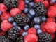 A close-up of vibrant red raspberries, deep purple blackberries, and blue blueberries, symbolizing healthy, antioxidant-rich nutrition.