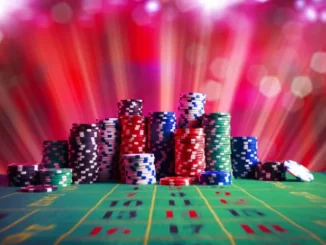 A vibrant image of numerous stacks of colorful casino chips (red, blue, green, black, white) on a green felt roulette table, with a blurred background of red and purple light streaks, suggesting an exciting casino atmosphere.