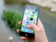 A hand holding an iPhone displaying various app icons, suggesting the use of mobile technology for learning.