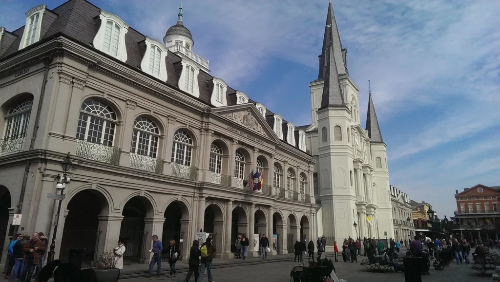 Jackson Square in New Orleans with historic buildings and a crowd of people under a partly cloudy sky.