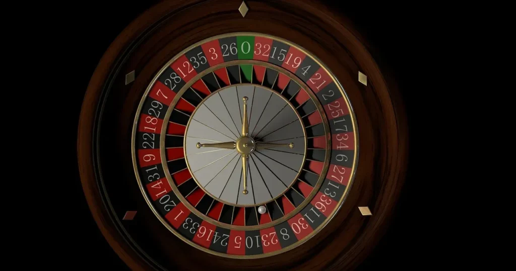 A high-angle, close-up shot of a classic wooden roulette wheel with red and black numbered slots, a green zero and double zero, and a silver ball resting in one of the numbered compartments against a solid black background.