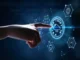 A finger touches a glowing cloud computing icon surrounded by digital interface elements on a dark blue background.
