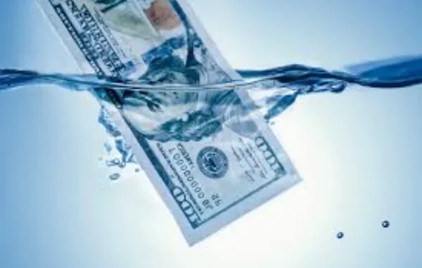 Saving Money on Your Water Bill: Effective Plumbing Tips to Reduce Water Usage and Costs A hundred-dollar bill partially submerged in clear blue water, with ripples and small splashes.