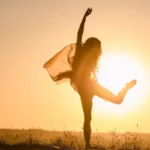 Silhouette of a happy woman dancing in the sunset, symbolizing freedom and body confidence after weight loss.