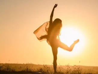 Silhouette of a happy woman dancing in the sunset, symbolizing freedom and body confidence after weight loss.