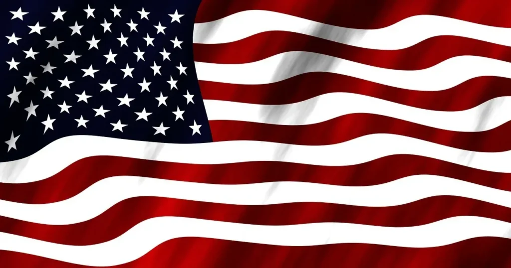 The American flag waving with its distinct red and white stripes and blue field with white stars.