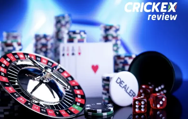 A close-up of a gambling table setup with a roulette wheel, dice, poker chips, and a dealer button, with the "CRICKEX review" logo in the top right corner.