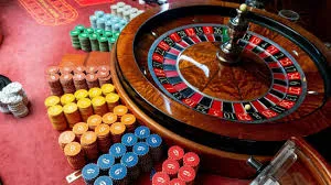 A close-up of a roulette wheel with colorful stacks of casino chips on a red felt table.