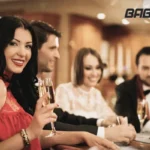 A group of stylishly dressed friends are enjoying drinks and conversation at a casino table, likely engaged in mobile gaming on their devices. The "BABU88" logo is visible in the upper right corner.