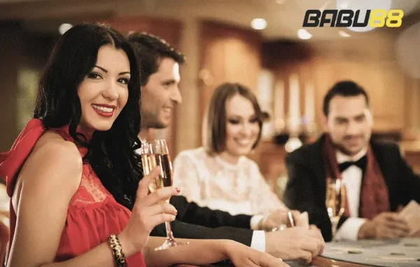 A group of stylishly dressed friends are enjoying drinks and conversation at a casino table, likely engaged in mobile gaming on their devices. The "BABU88" logo is visible in the upper right corner.
