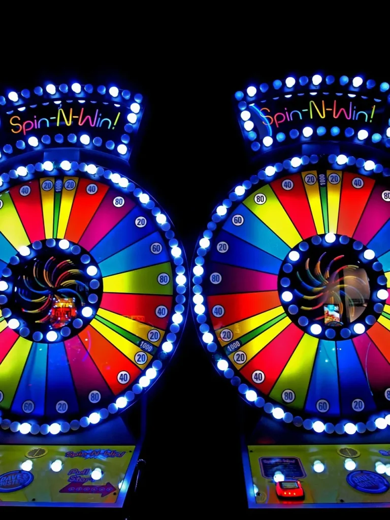 A pair of brightly lit "Spin-N-Win" arcade-style game wheels, showcasing a variety of colored segments and numbers, which conceptually represents the bonus features and games in modern slots.