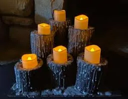 A group of electronic Halloween candles shaped like pillars with a dark, waxy, and dripping texture, arranged on a black surface.