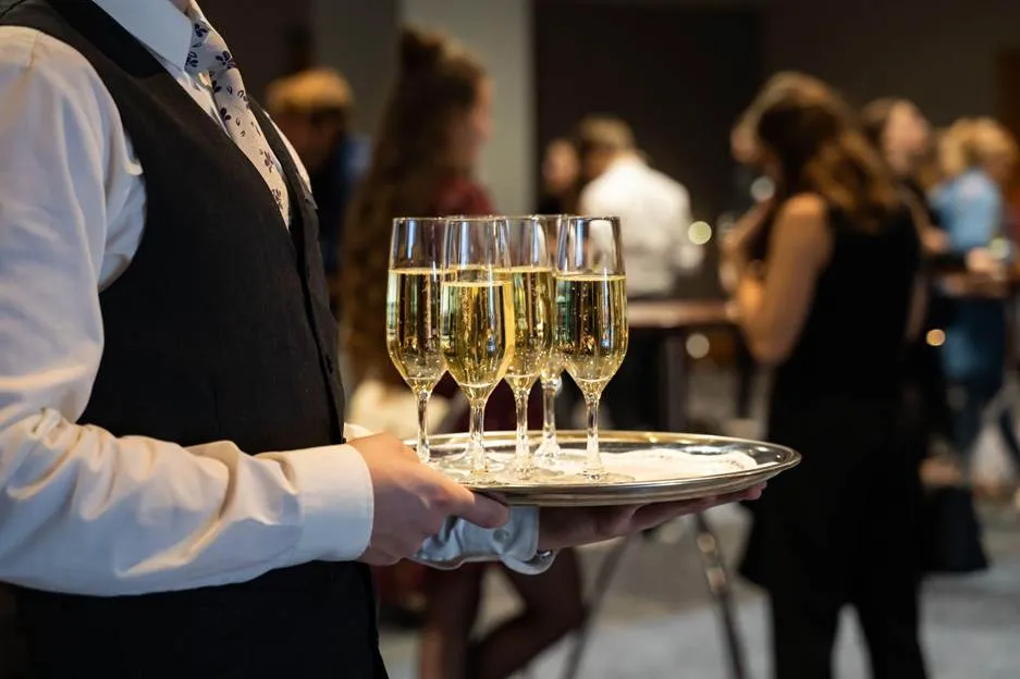 Waiter at a banquet holding champagne flutes.