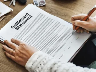 A person's hands are shown signing a "Settlement Statement" document with an orange pen, indicating the finalization of a legal or insurance agreement.