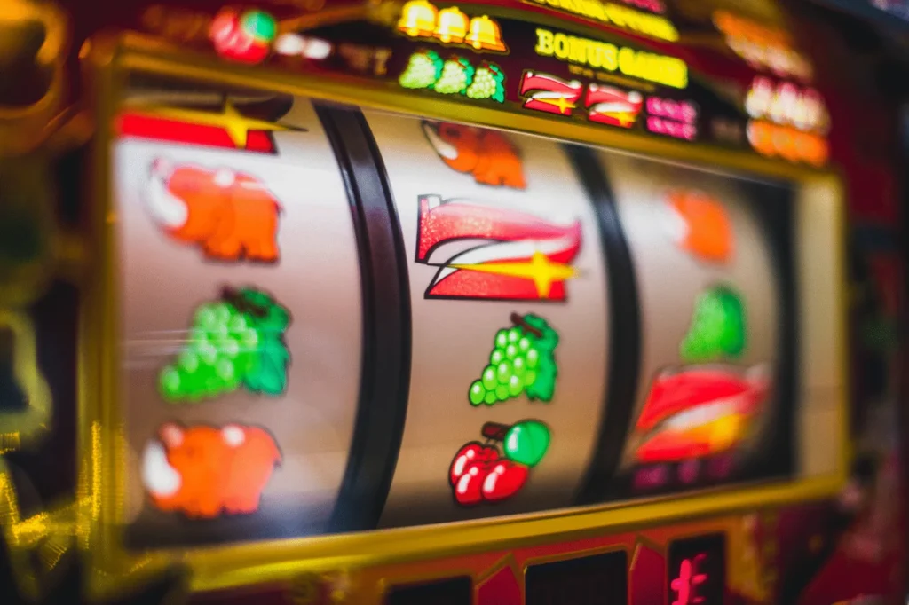 A close-up view of the spinning reels of a vibrant, fruit-themed slot machine, highlighting the colorful symbols and a "BONUS GAME" display.