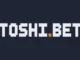 A pixelated logo with white blocky letters spelling "TOSHI.BET" on a dark background, with a small orange square replacing the dot on the "i".