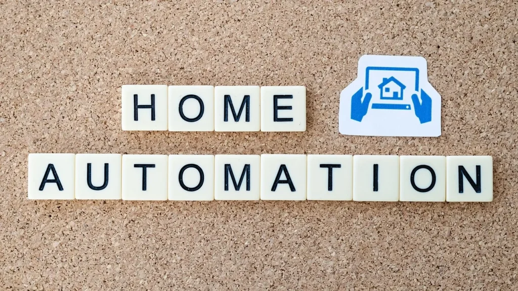 The words "HOME AUTOMATION" are spelled out in letter tiles on a cork board, with an icon of a house and a laptop above it, symbolizing smart tools for home upgrades.