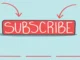 A hand-drawn illustration of a red button with the word "SUBSCRIBE" on it, with two red arrows pointing down.