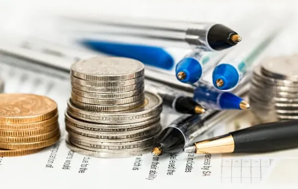 Financial Planning and Term Insurance Coverage Stacks of silver and gold coins next to several pens on a printed document, symbolizing financial planning.